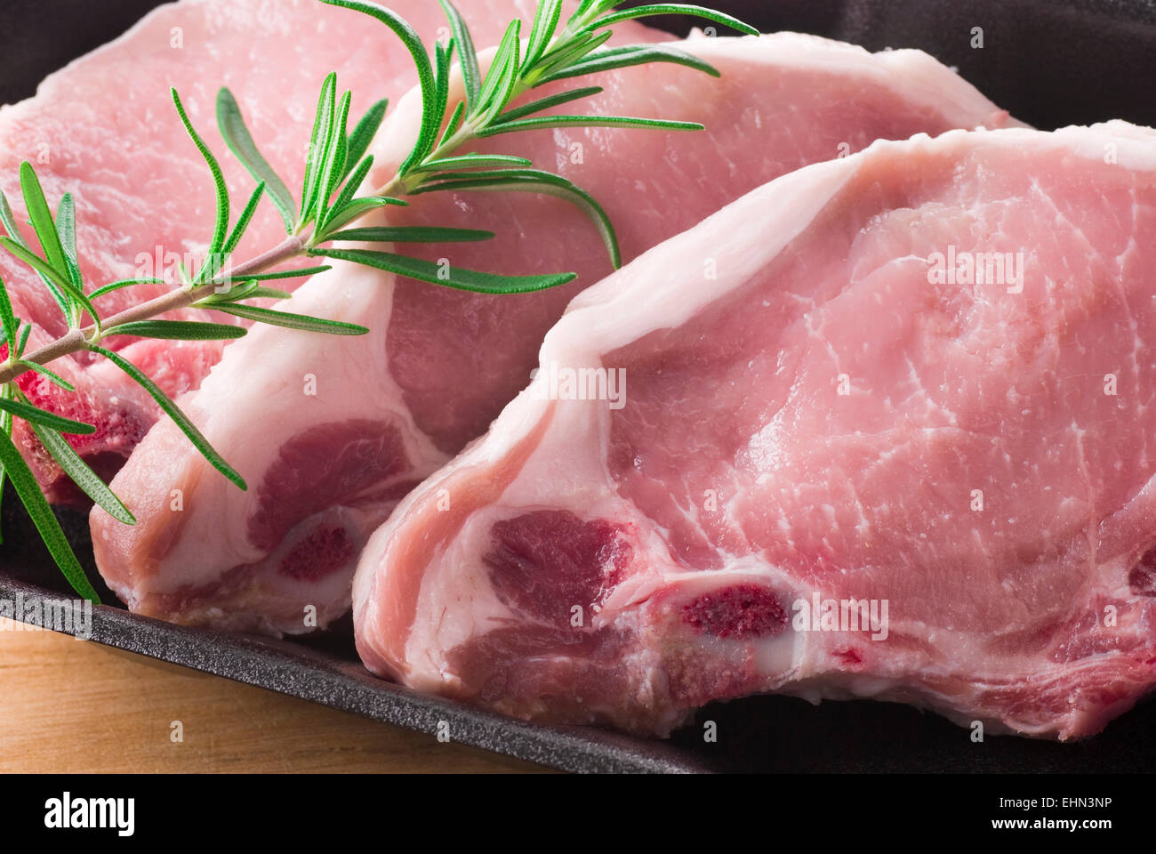 Three pork chops with a rosemary branch. Stock Photo