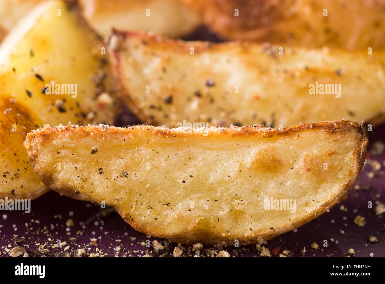 Roasted potato with salt and red, black and white pepper. Stock Photo
