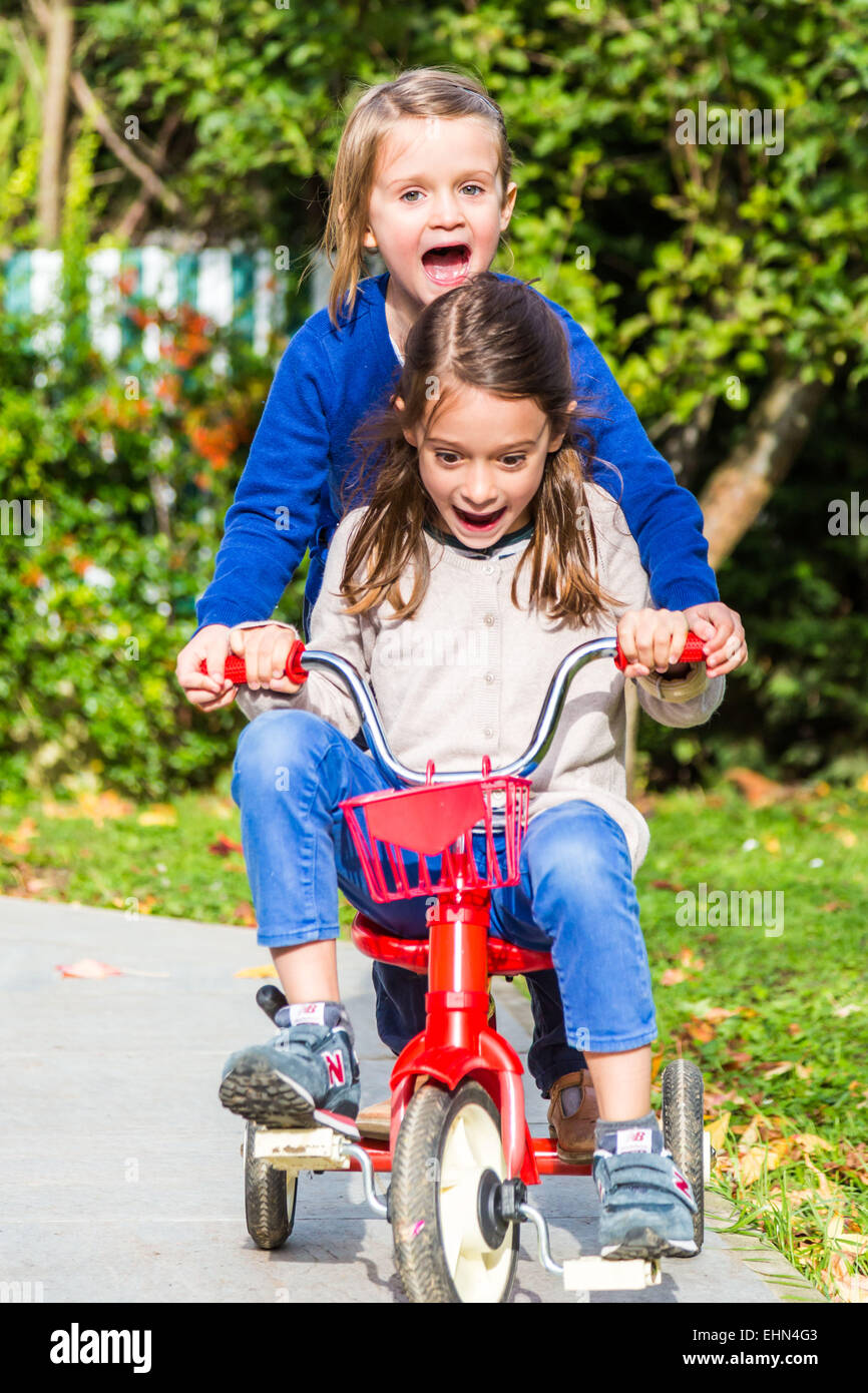 5 and 7 years old girls riding a bicycle. Stock Photo