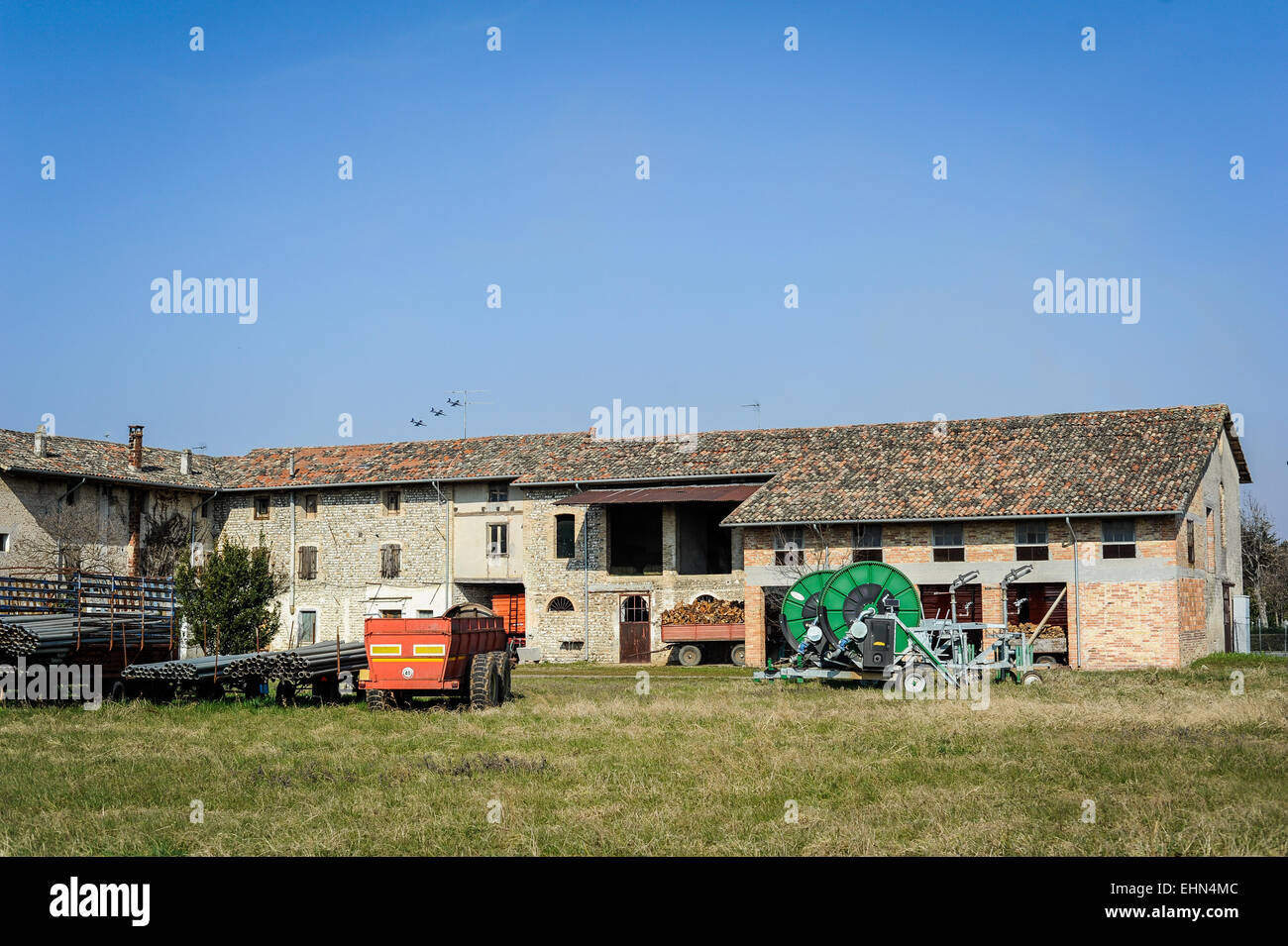 Sprinkler system with pipes and in the background an old farm Stock Photo