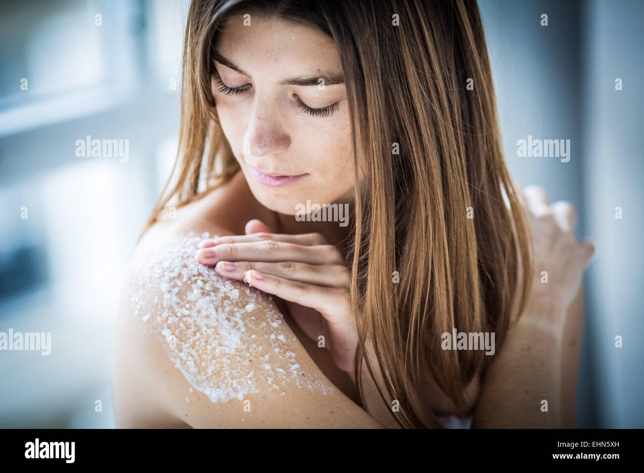 Woman using exfoliating scrub treatment. Stock Photo