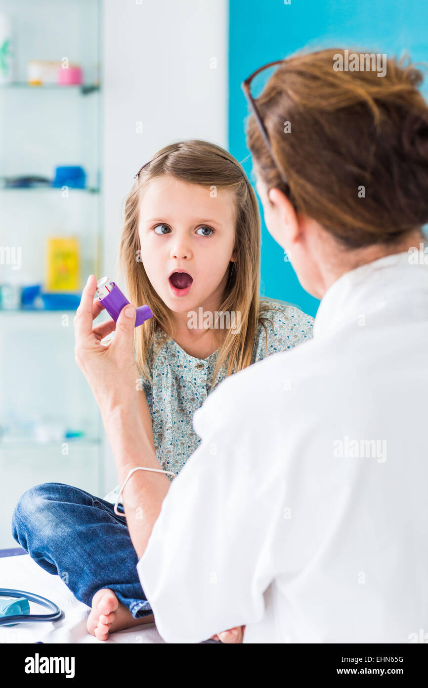 Doctor instructing a girl on how to use an asthma inhaler. Stock Photo