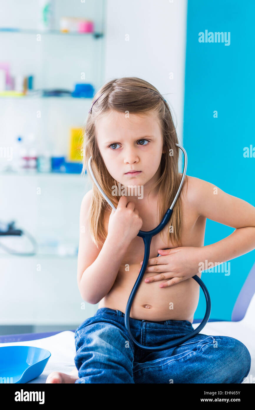 Girl using a stethoscope to listen to her chest. Stock Photo