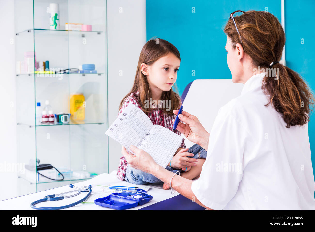Diabetic 7-year- old girl listening to her doctor explain how to use a type of insulin syringe. Stock Photo