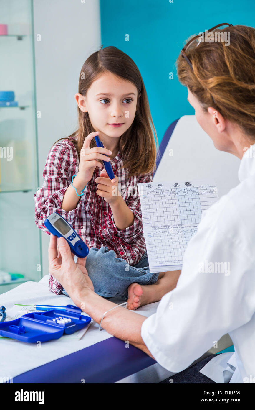 Diabetic 7-year- old girl listening to her doctor explain how to use a type of insulin syringe. Stock Photo
