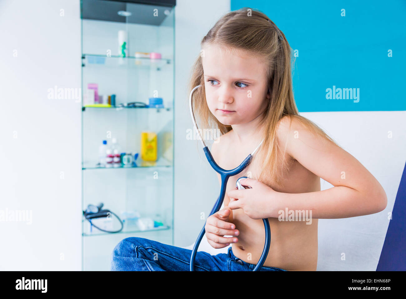 Girl using a stethoscope to listen to her chest. Stock Photo