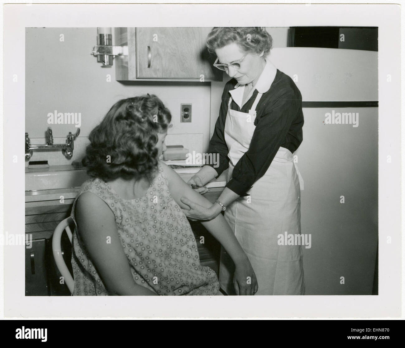 Nurse in front of refrigerator, immunizing seated woman, 1960's Stock Photo Alamy
