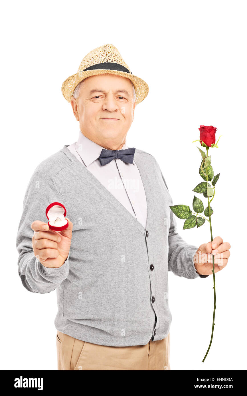 Senior gentleman holding an engagement ring and a red rose isolated on white background Stock Photo