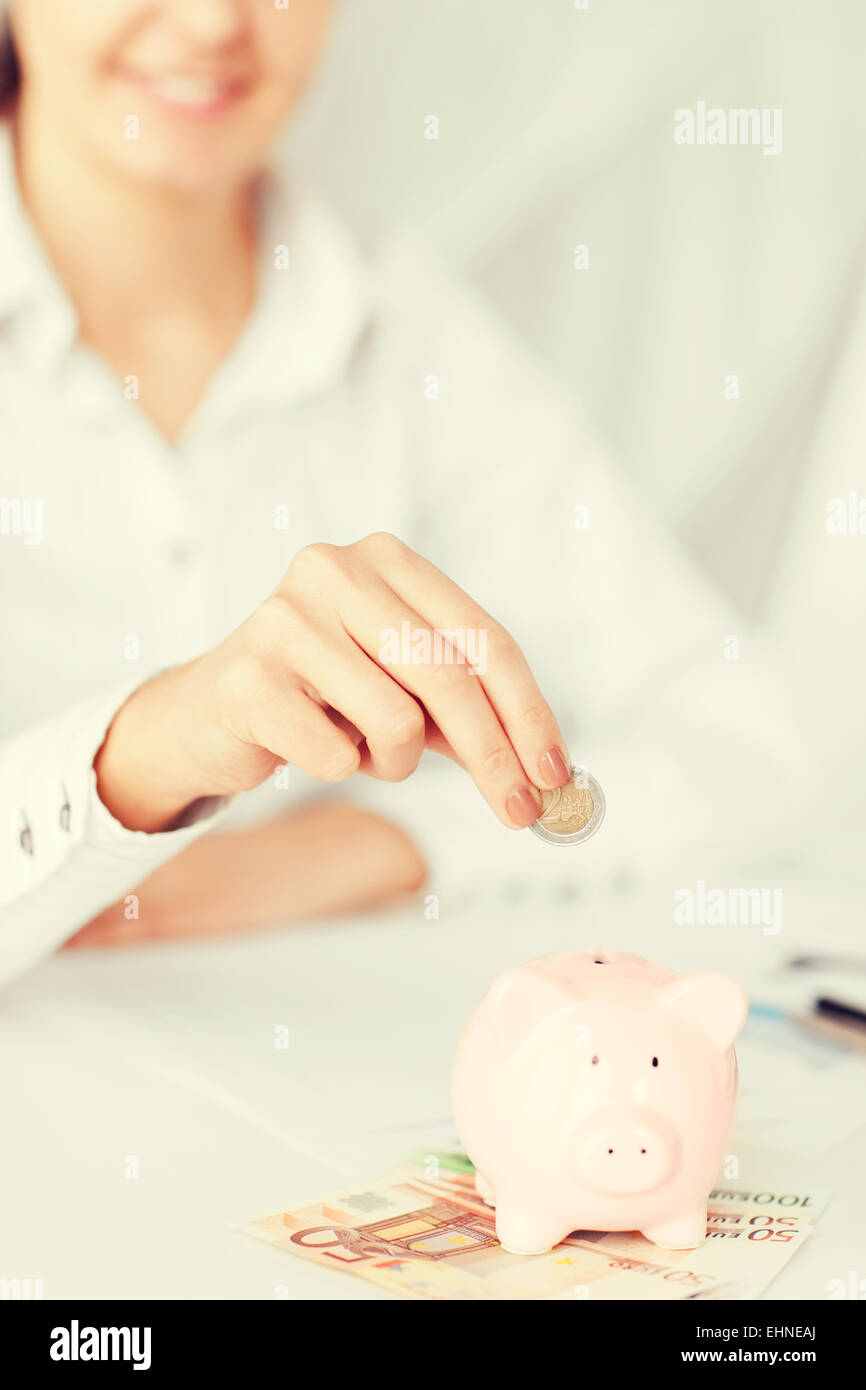 woman hand putting coin into small piggy bank Stock Photo - Alamy