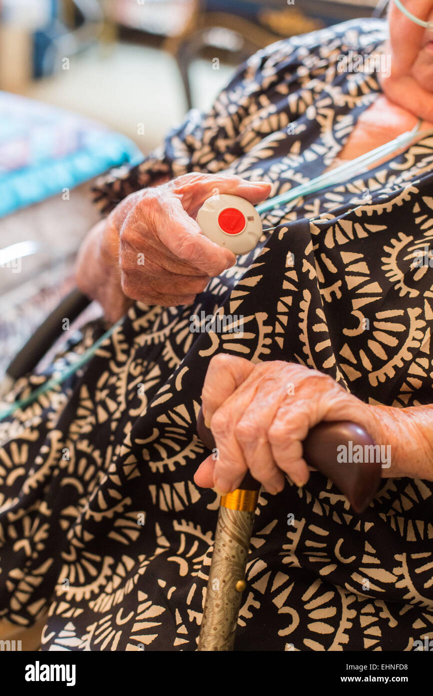 Emergency call button. Elderly woman wearing a remote assistance unit at home. Stock Photo