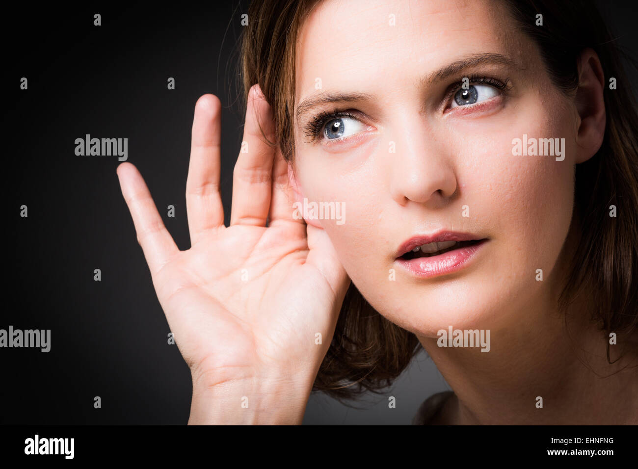 Woman holding hand to her ear. Stock Photo