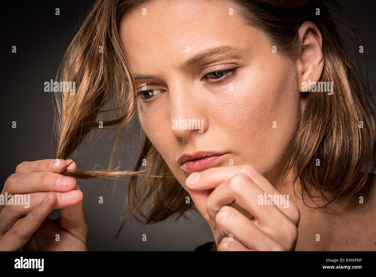 Woman inspecting the tip of her hair. Stock Photo