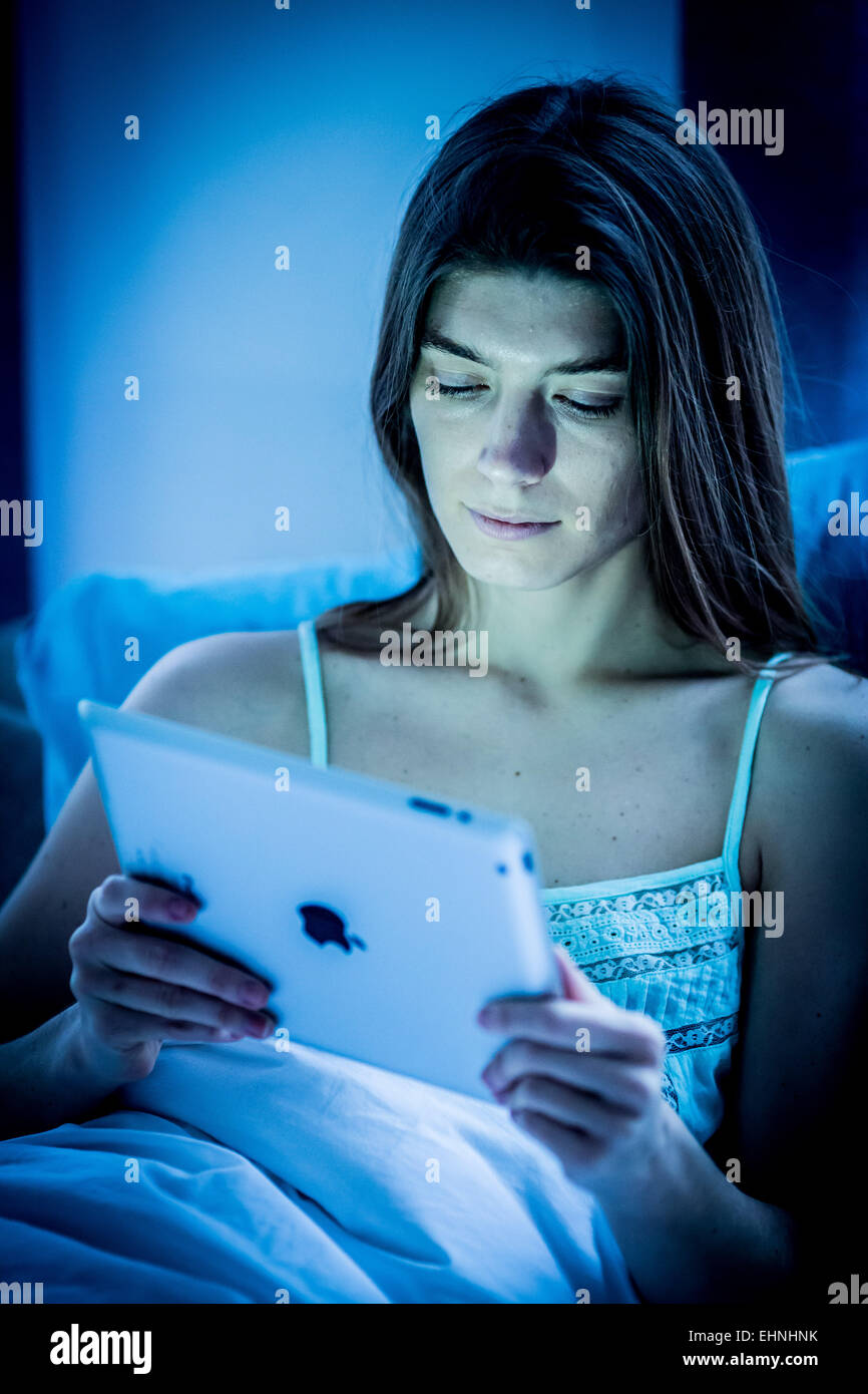Woman using a digital tablet at night. Stock Photo