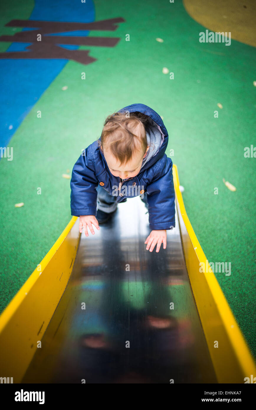 18 month-old baby boy on a slide in a playground. Stock Photo
