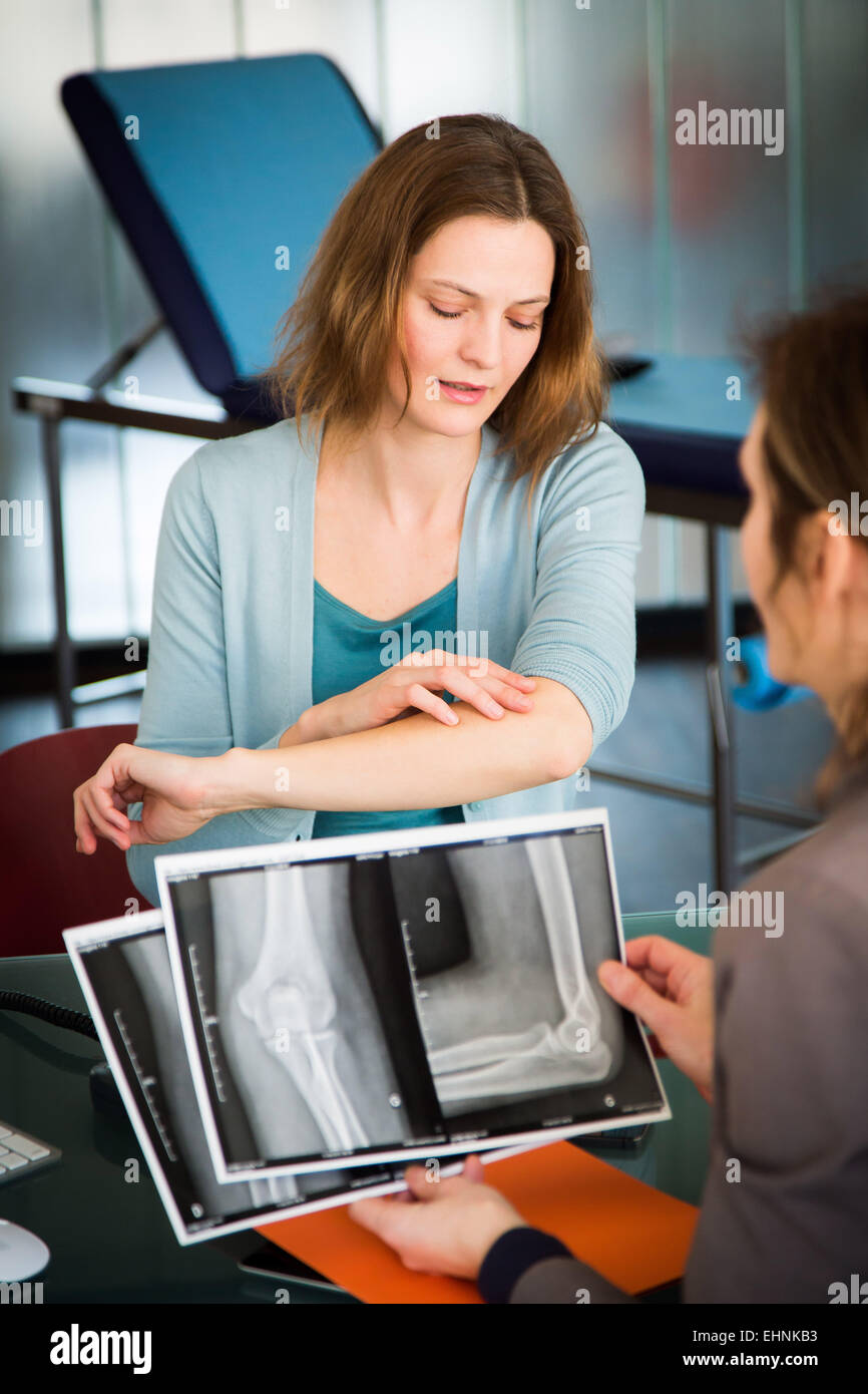 Doctor examining and commenting patient's elbow X-ray. Stock Photo