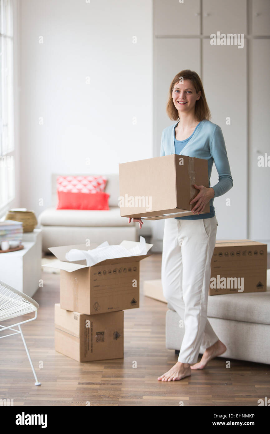 Woman carrying moving boxes in her new home. Stock Photo