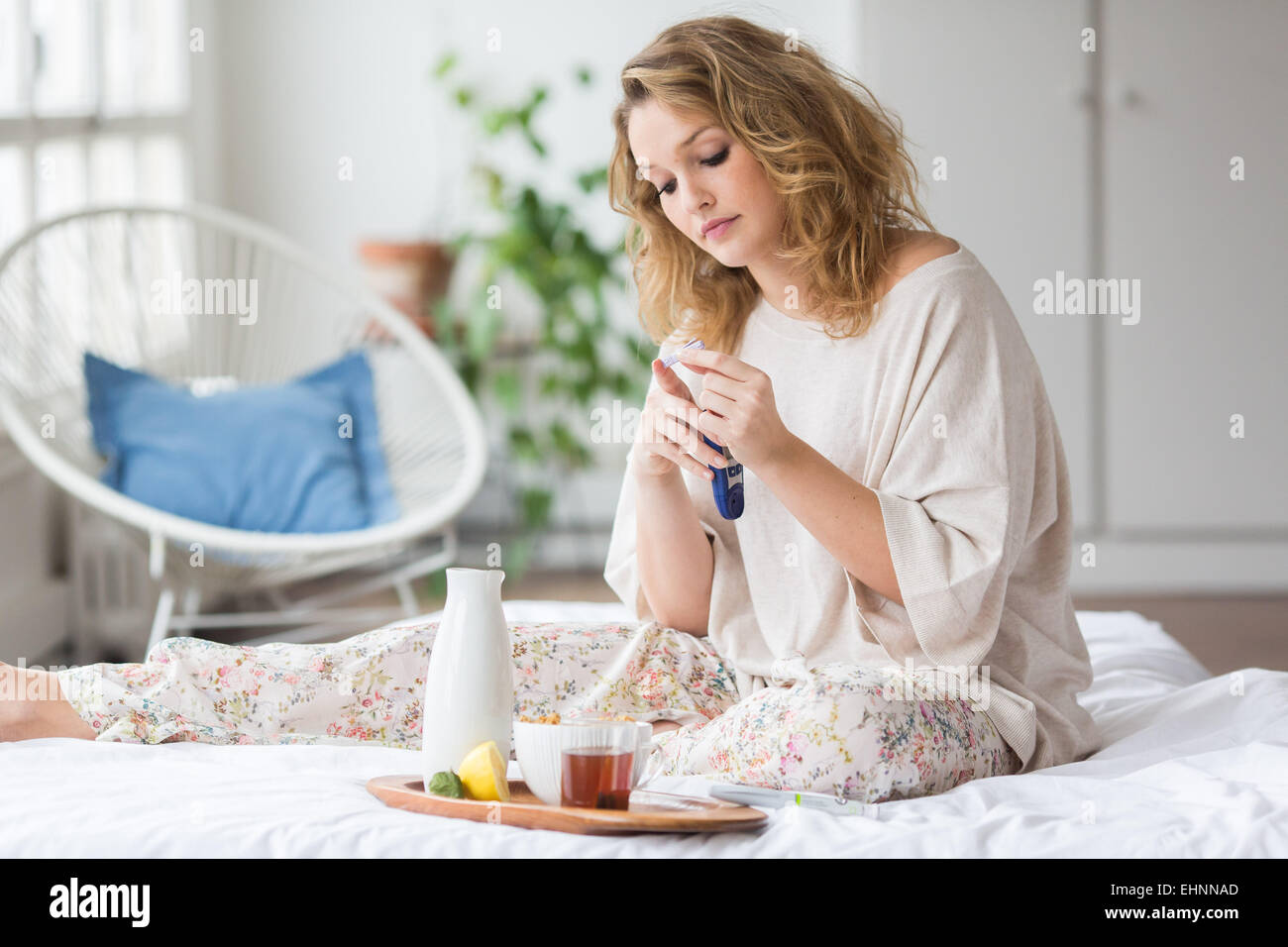 A diabetic person is checking her blood sugar level (self glycemia)with glucometer before breakfast. Stock Photo