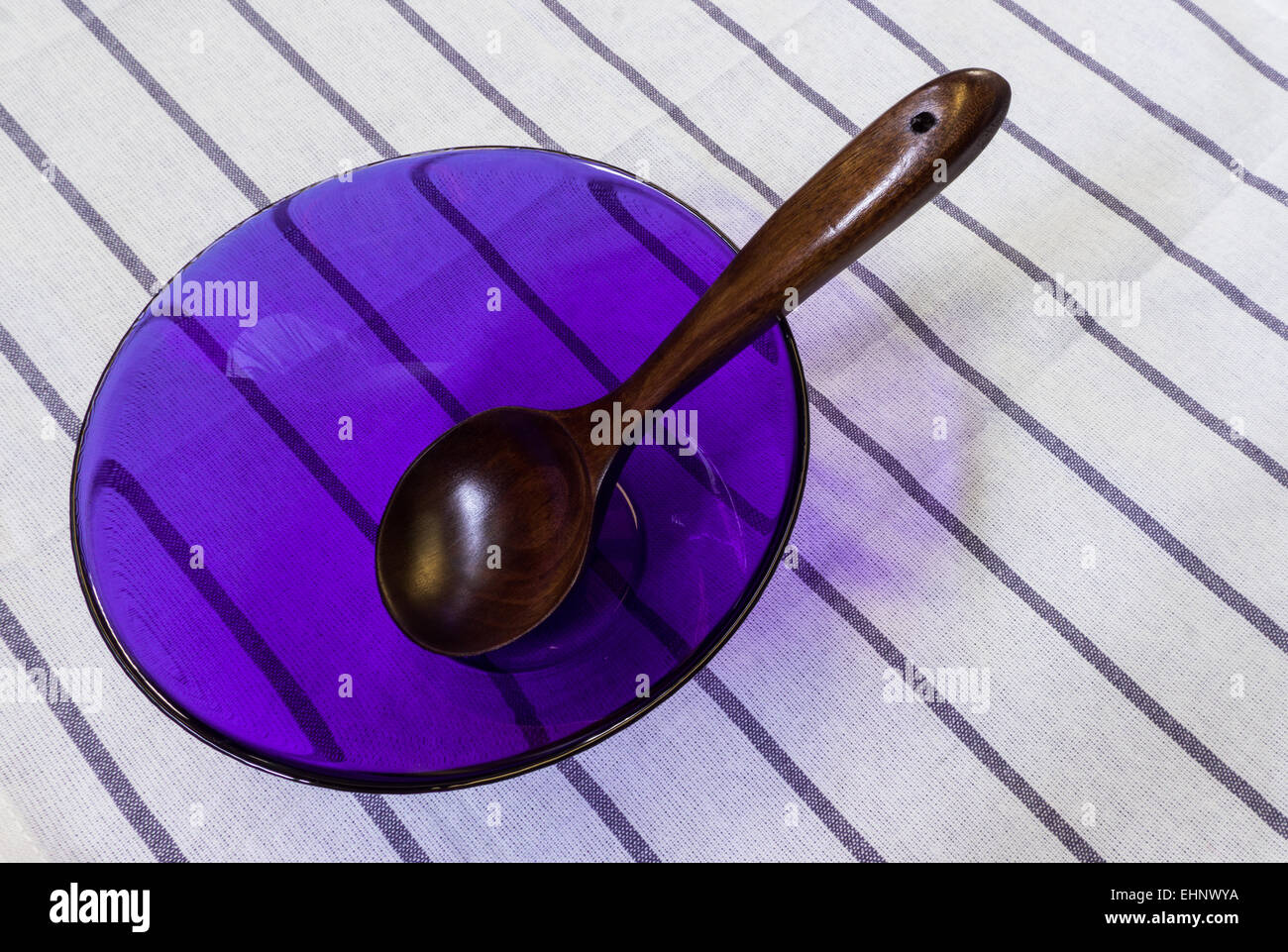 Wooden Spoon in Light Purple Cooking Glass Bowl Placed on White Table Background Stock Photo