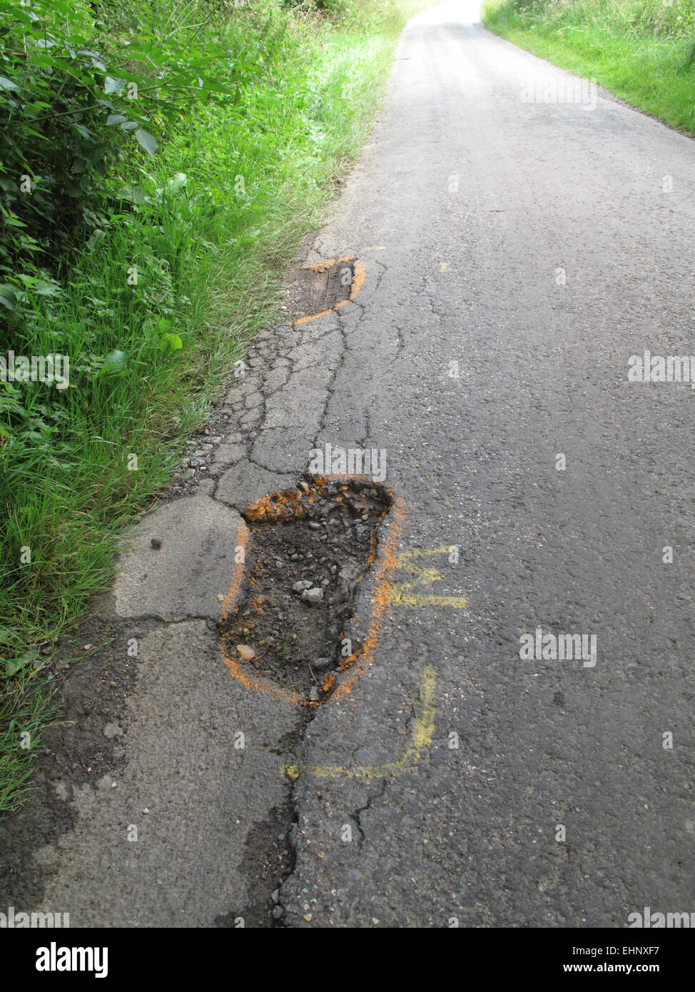 Potholes in broken tarmac country road  marked to warn cyclists of the danger, Berkshire, July Stock Photo