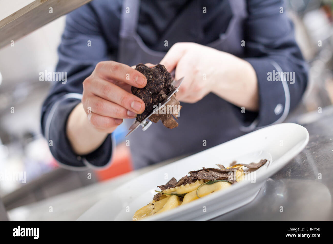 Chef grating truffle mushroom shavings onto homemade ravioli in a