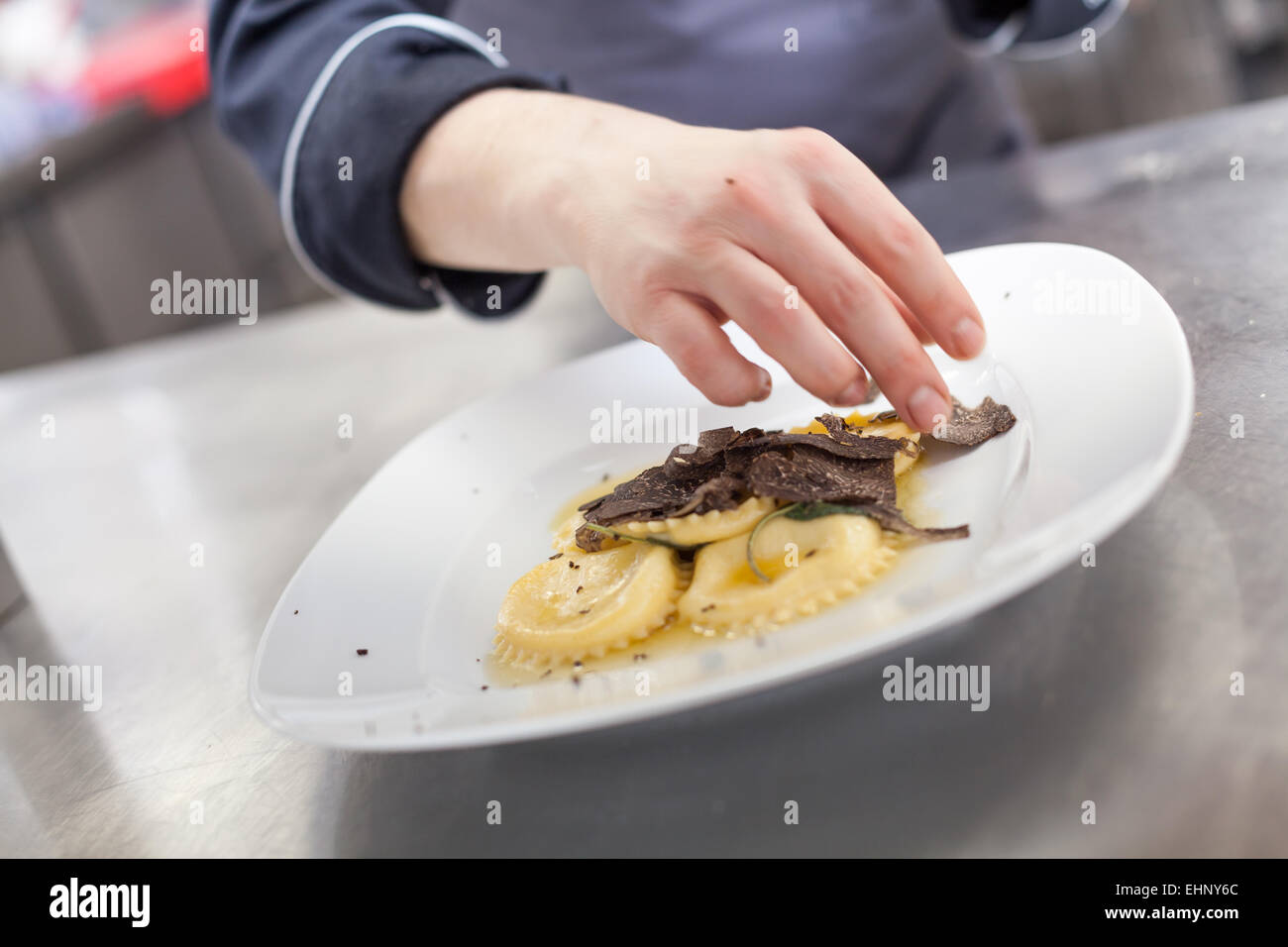 Chef grating truffle mushroom shavings onto homemade ravioli in a