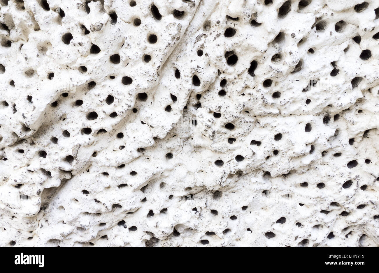 White Concrete Rock Wall with Deep Black Holes on Background Stock Photo