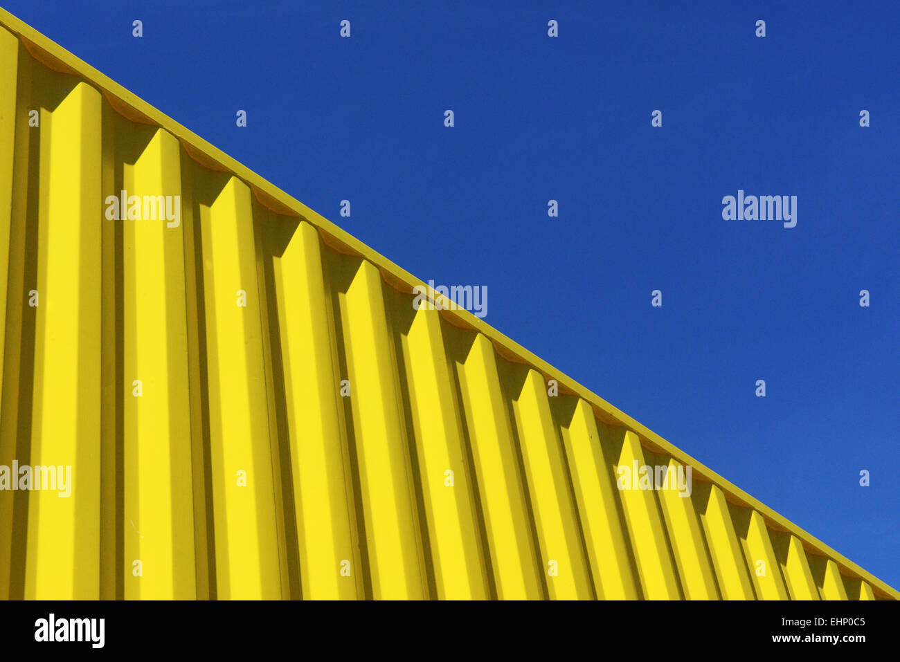 Bright Yellow shipping container juxtaposed against a bright blue sky Stock Photo