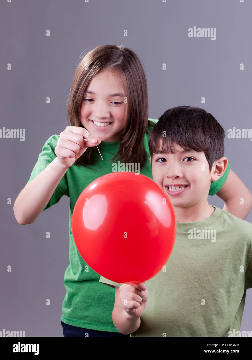 Popping her brother's balloon. Stock Photo