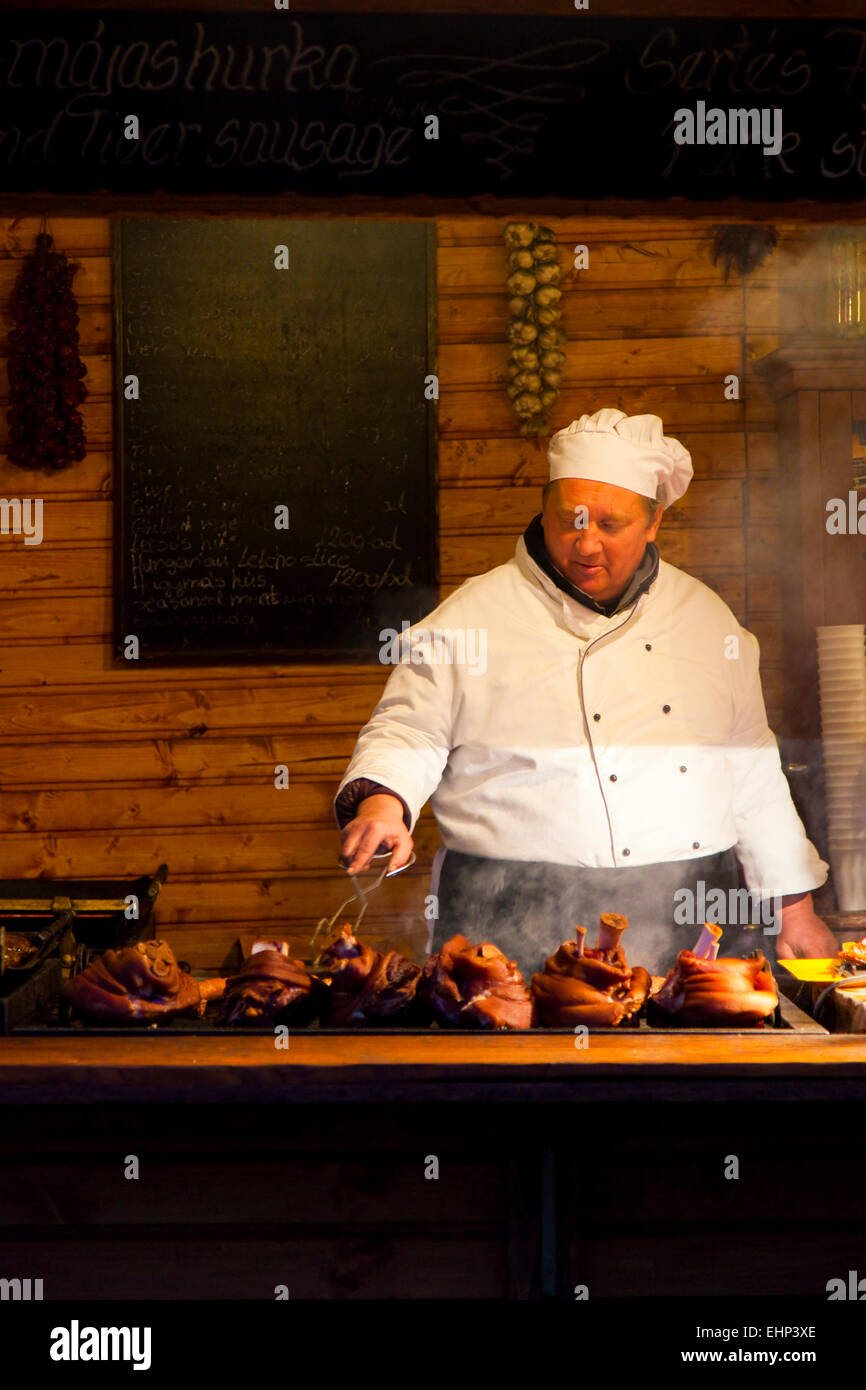 A chef cooks meat on a grill at a Christmas Market in Budapest, Hungary Stock Photo