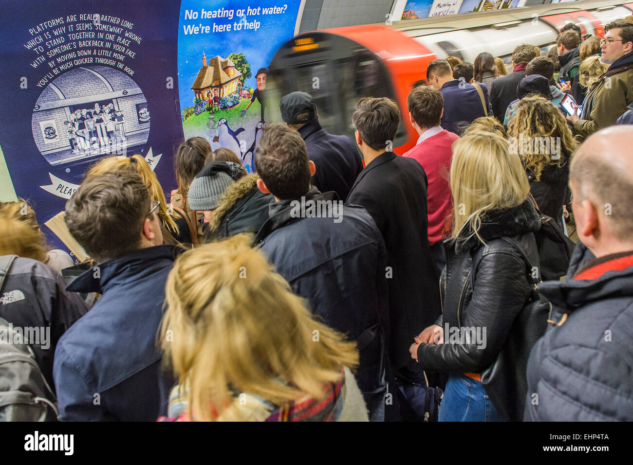 London, UK. 16th March, 2015. Passengers await packed Northern Line trains at Stockwell station. They are bombarded by announcements that all lines have a good service and are faced by a helpful sign, put up by TFL, telling them not to crowd around one door. Unfortunately they are forced by weight of numbers to stand perilously close to the platform edge.  Stockwell Station on the Northern Line, London Unerground, 16 Mar 2015. Credit:  Guy Bell/Alamy Live News Stock Photo