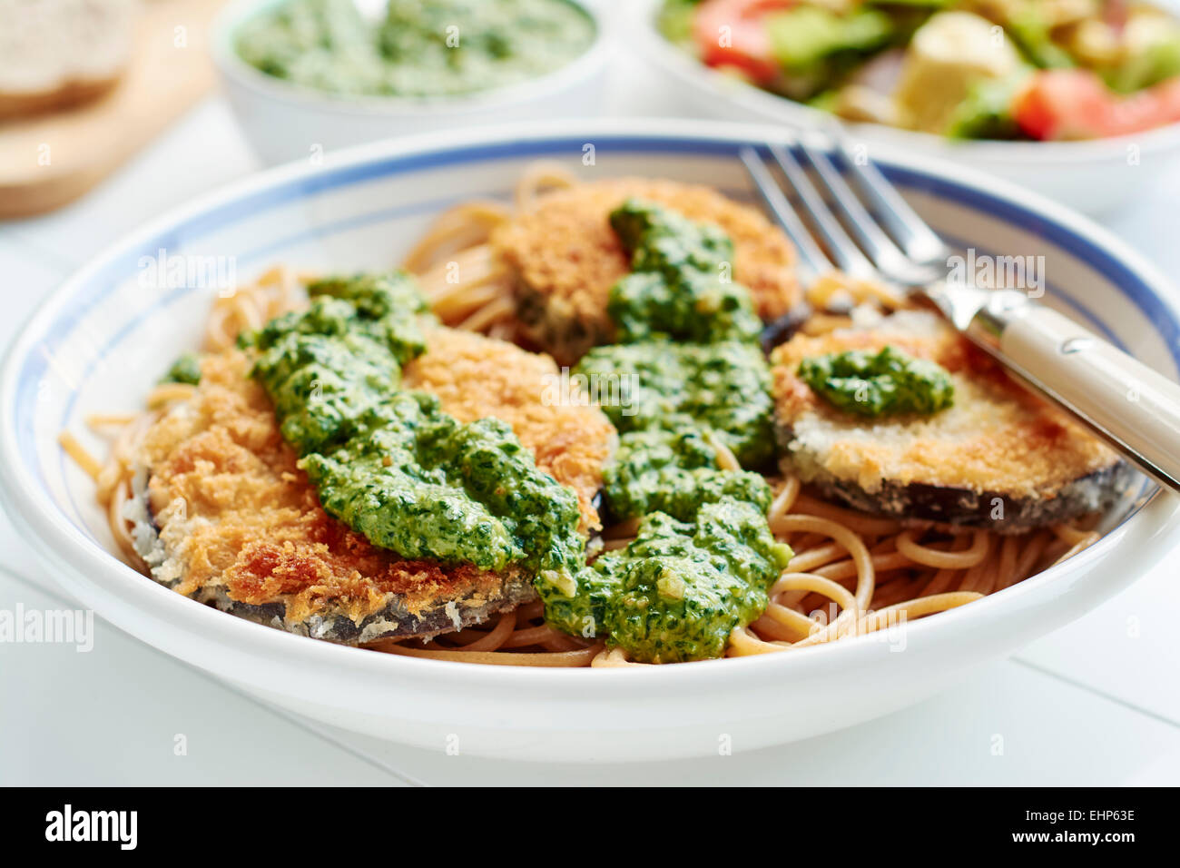 Breaded eggplant with spinach pesto on spaghetti Stock Photo