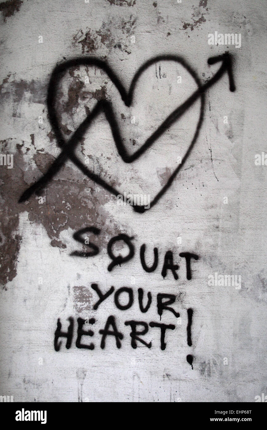 A graffiti stating 'Squat Your Heart'. Stock Photo
