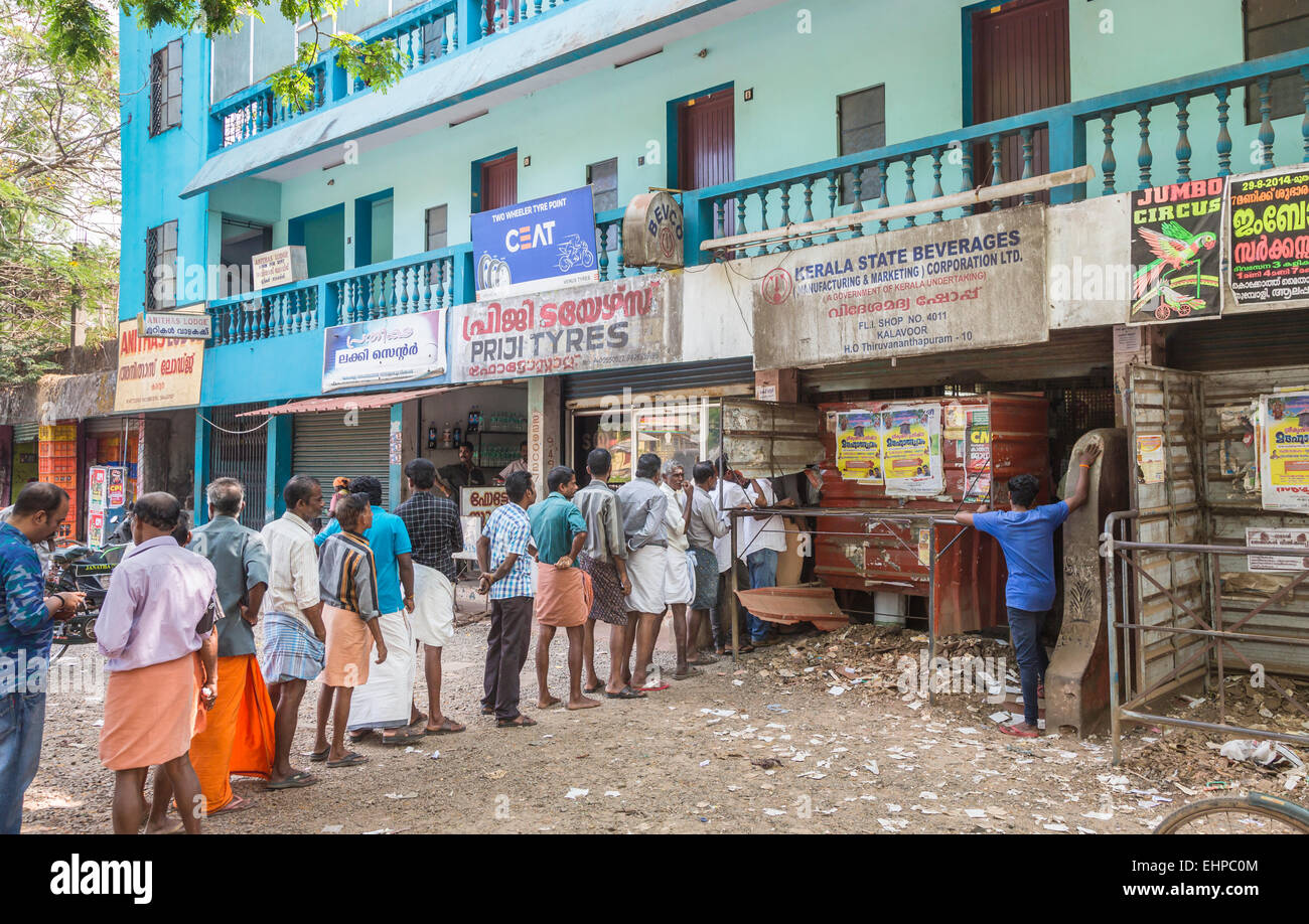 Local people patiently queue in line to buy beer, wine and other alcoholic drinks in a state licensed shop in Cochin (Kochi), Kerala, southern India Stock Photo