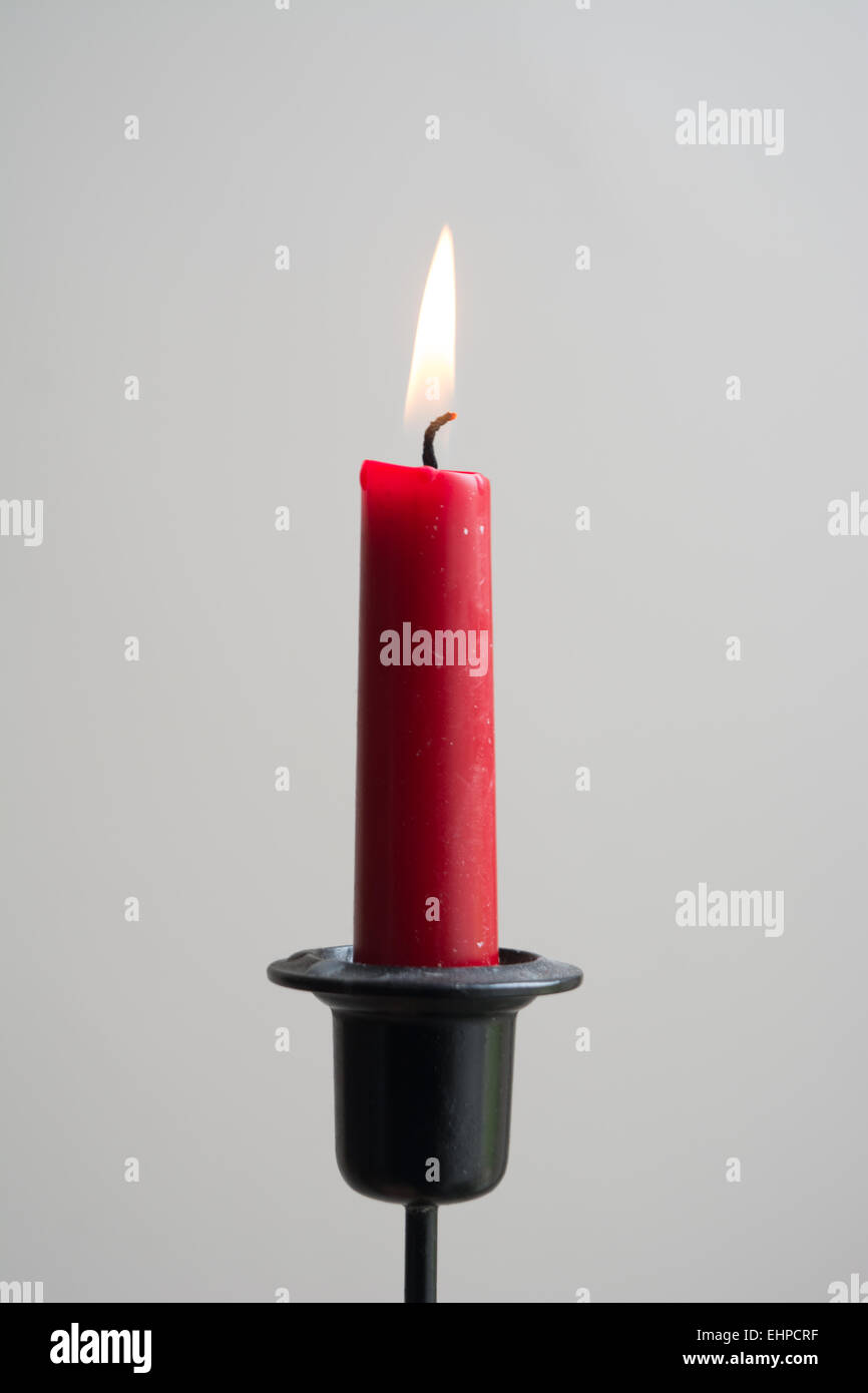 Single red candle with flame in black candleholder Stock Photo