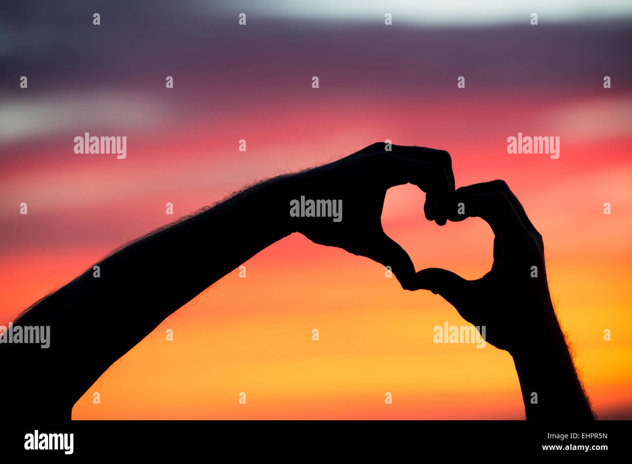 Heart hands gesture at sunrise. Silhouette Stock Photo