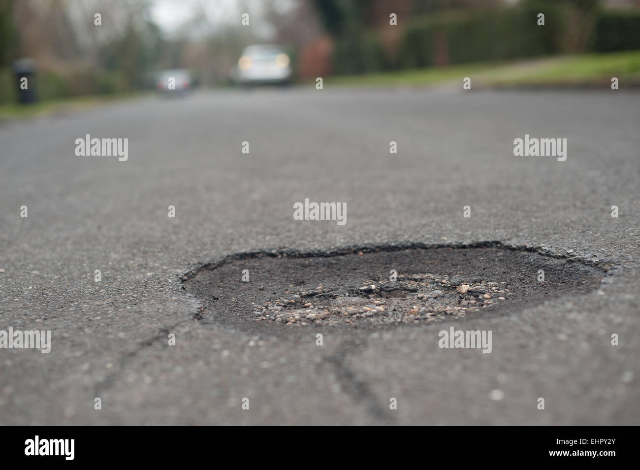 In need of repair a pothole appears in the middle of a tarmacked road surface creating a hole to throw cyclists off accidents Stock Photo