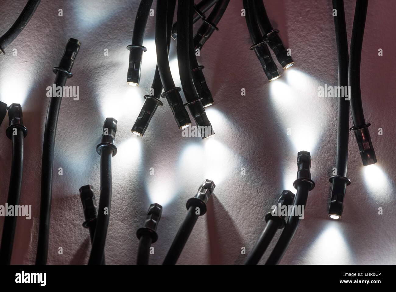 Mini lights tips ends of optical glassfibre optic cables illuminating a small spotlight area with bright light and dark shade Stock Photo