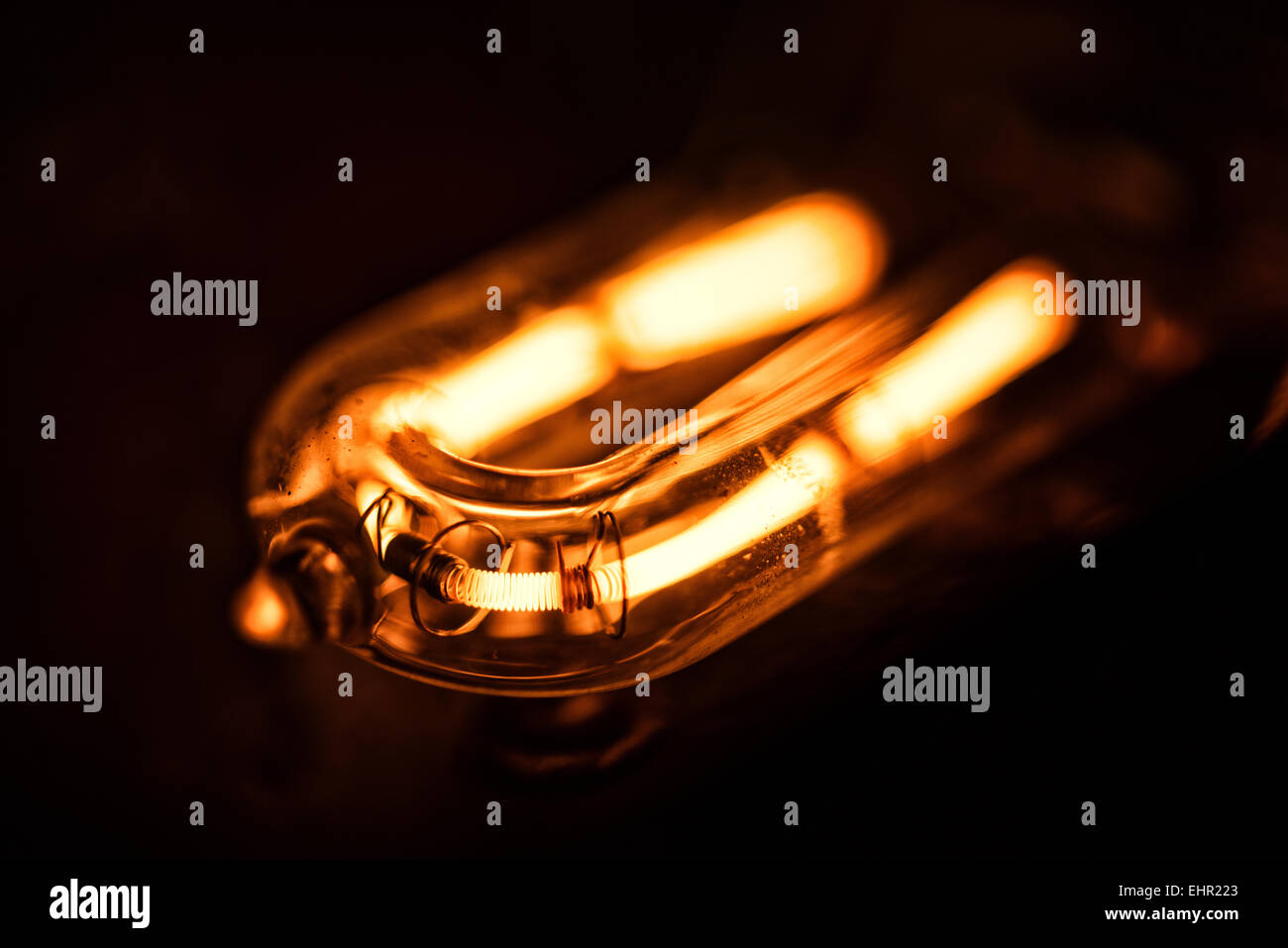 glowing filament of a 1000 quartz halogen bulb with flaked metal and heat damage to the reflector and heat dispenser Stock Photo