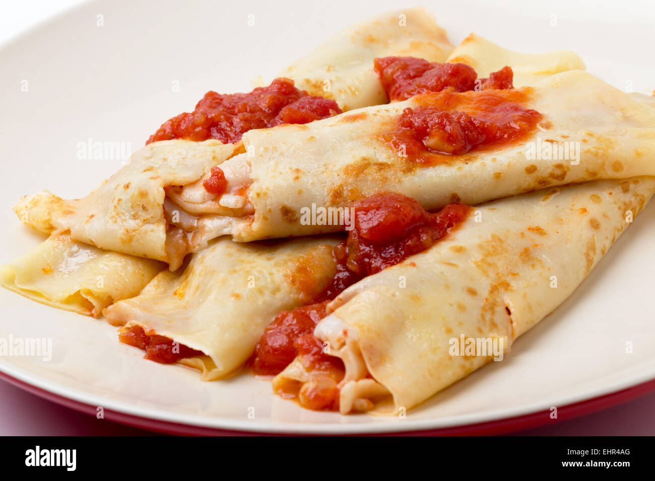 Savory pancakes filled with goats cheese and tomato salsa and garnished with more sauce. Stock Photo