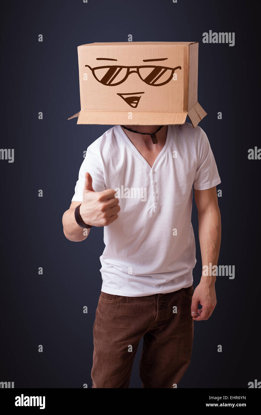 Young man gesturing with a cardboard box on his head with smiley face ...