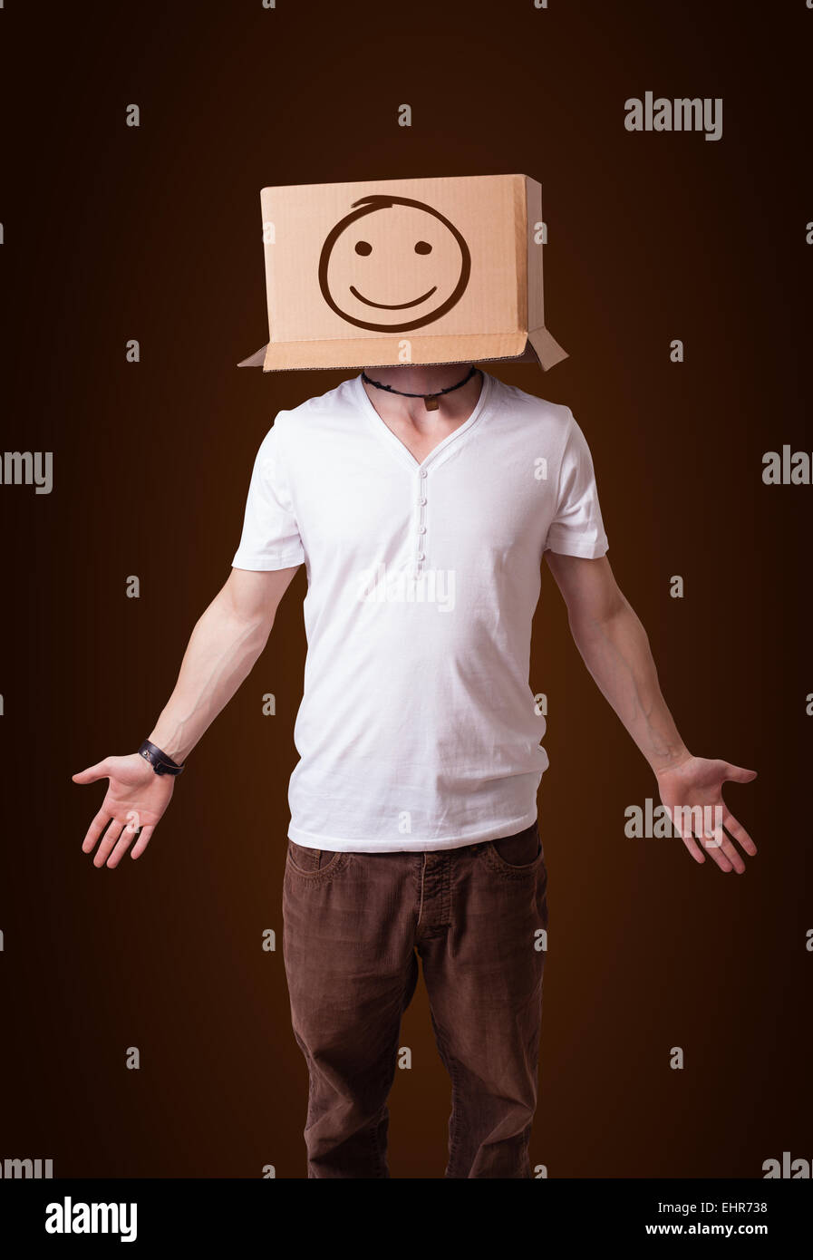 Young man gesturing with a cardboard box on his head with smiley face ...