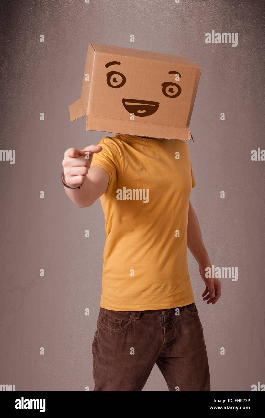 Young man gesturing with a cardboard box on his head with smiley face ...