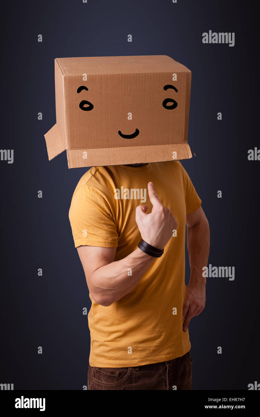 Young man gesturing with a cardboard box on his head with smiley face ...