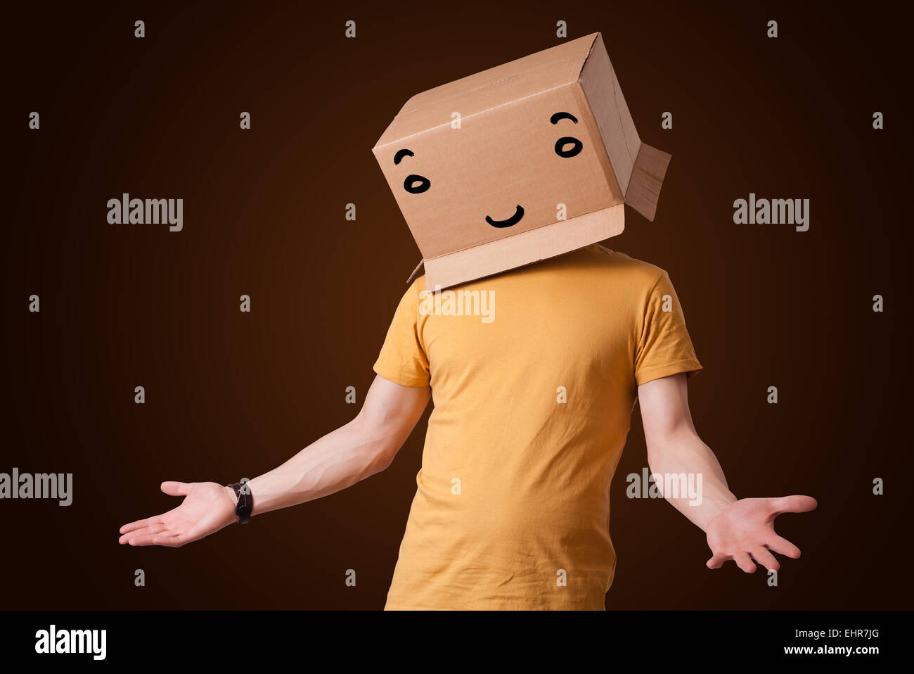 Young man gesturing with a cardboard box on his head with smiley face ...