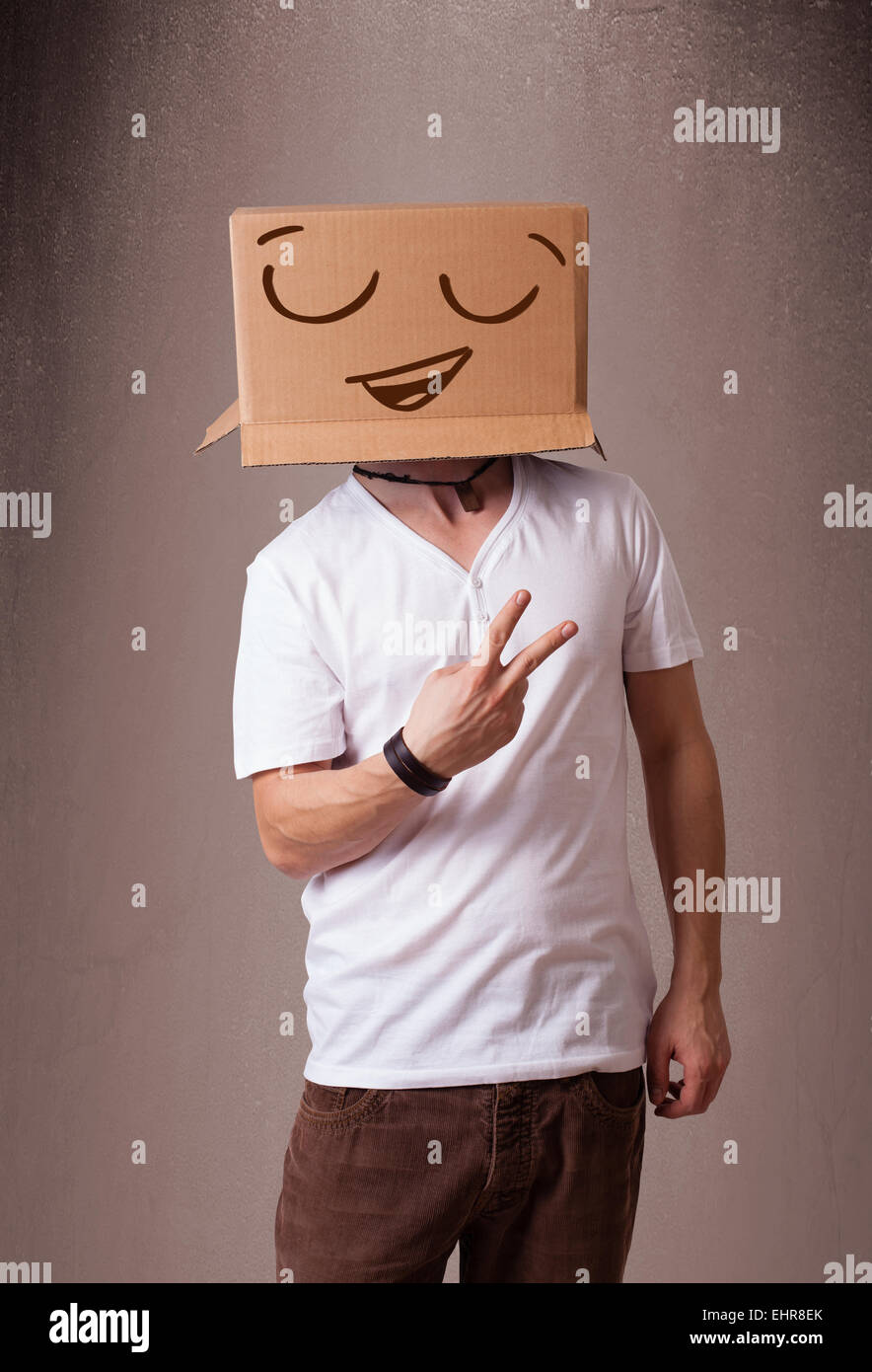 Young man gesturing with a cardboard box on his head with smiley face ...