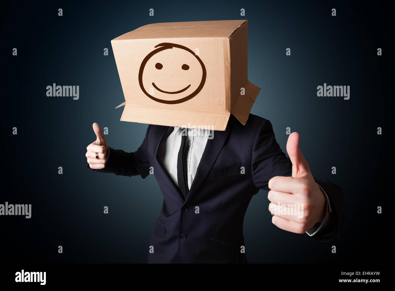 Businessman gesturing with a cardboard box on his head with smiley face ...
