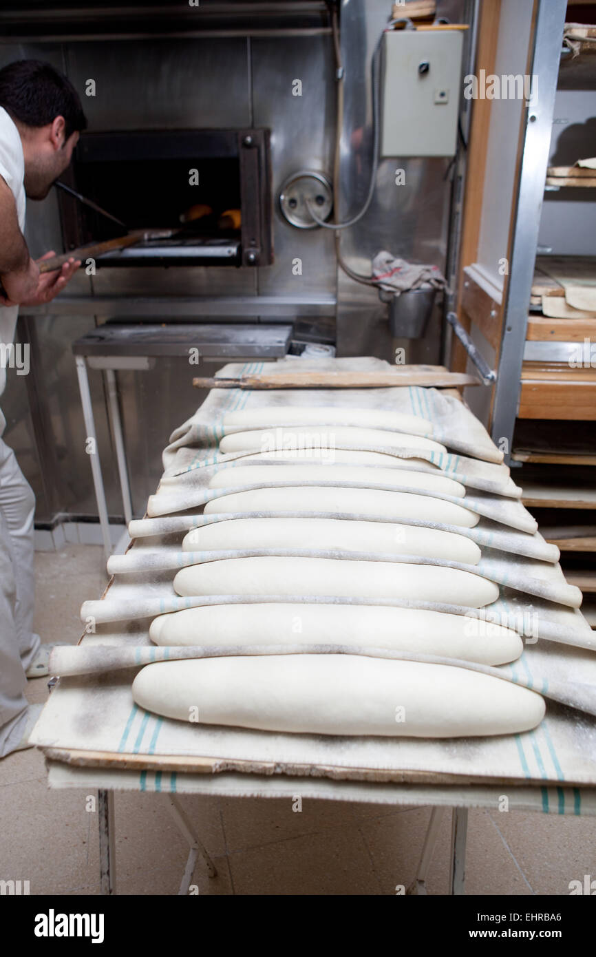 Baker putting kaiser roll dough into the oven. Manufacturing process of