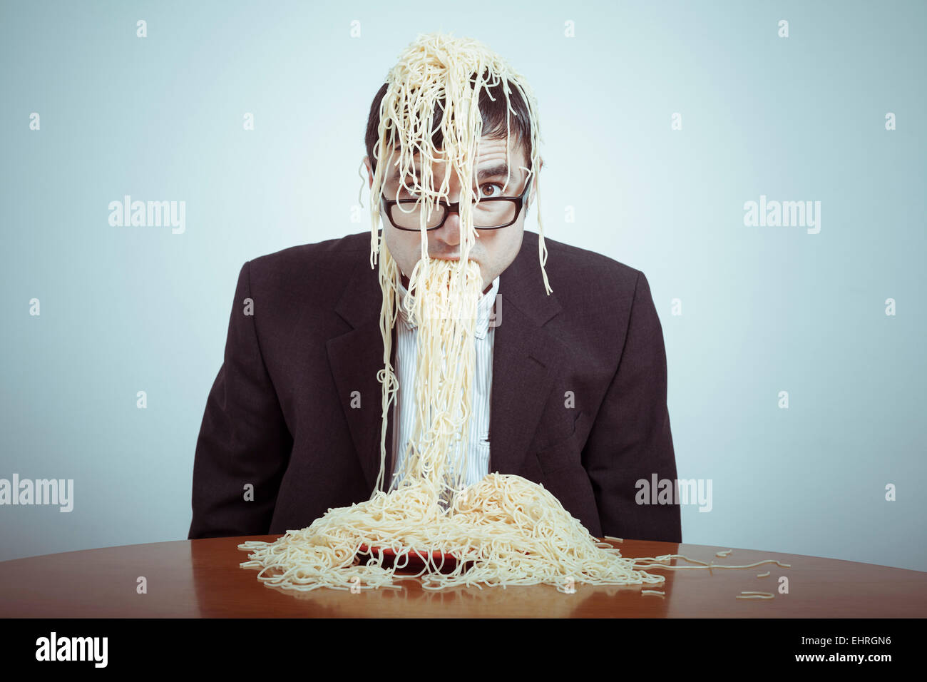 Overeating and consumerism concept. Nasty businessman eating pasta. Stock Photo