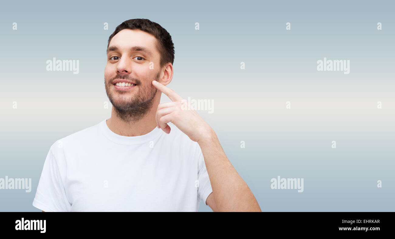 smiling young handsome man pointing to cheek Stock Photo