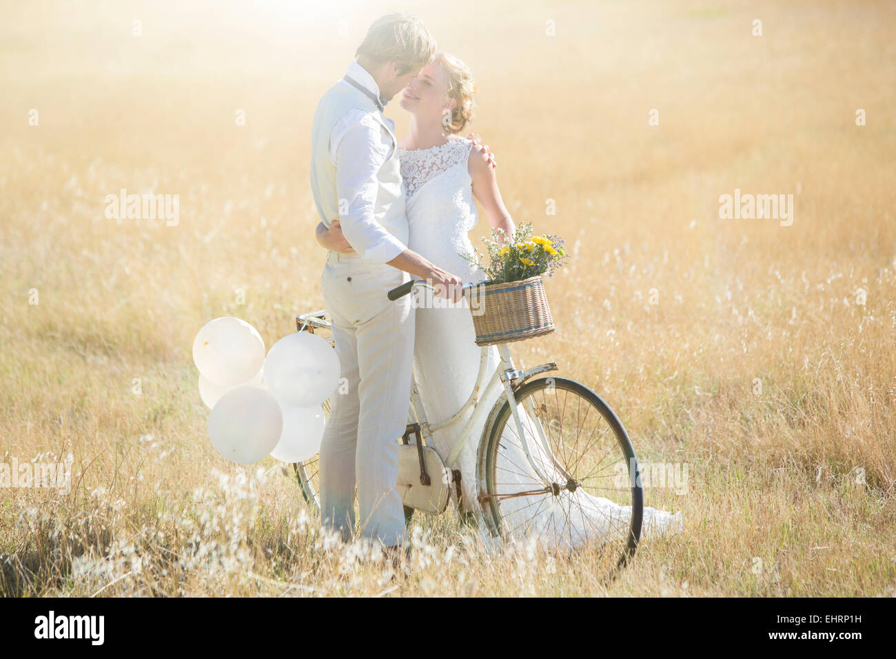 Young couple with bike kissing in meadow Stock Photo